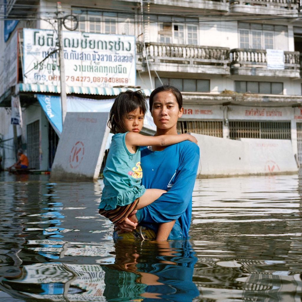 Woman holding child in flooded street