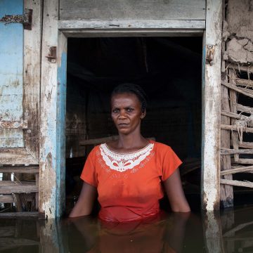 Adlene Pierre, aged 35, faces the camera in the doorway of her flooded house in Savanne Desole on the outskirts of the city of Gonaives.